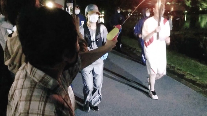 Người phụ nữ Nhật Bản dùng súng phun nước vào đuốc Olympic, phản đối Thế vận hội - Ảnh 2.